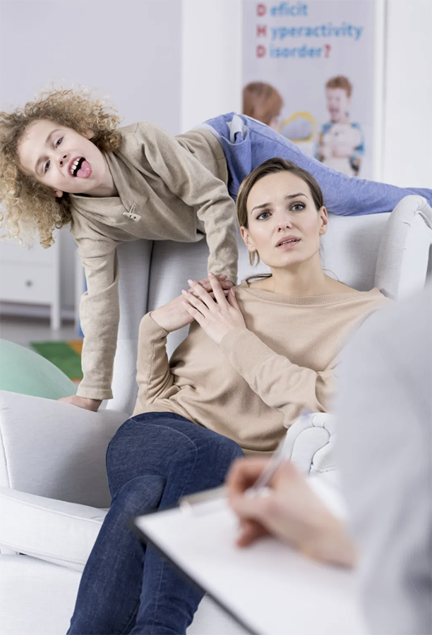 Child with ADHD behind parent at doctor visit